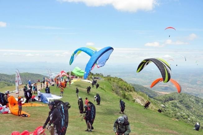 Pilotos preparando parapentes coloridos na rampa