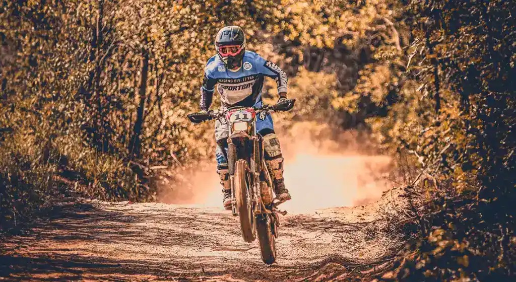 Piloto de moto off-road levantando poeira em trilha